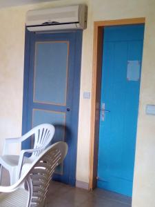 a room with a blue door and a white chair at Princess des Iles in Sainte-Anne