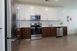 a kitchen with stainless steel appliances and wooden cabinets at Stunning Nulu 1BR CozySuites 05 in Louisville