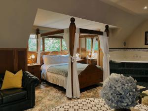 Arnica Views Summit Retreat في ماونت داندينونج: غرفة نوم مع سرير مظلة وحوض استحمام
