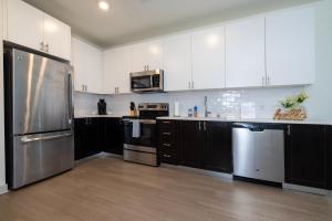 a kitchen with white cabinets and stainless steel appliances at Stunning Nulu 1BR CozySuites 06 in Louisville