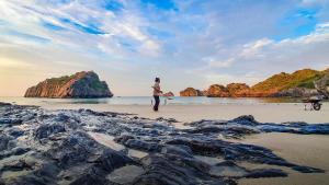 a person standing on a beach with rocks at Cat Ba Violet Hotel in Cat Ba