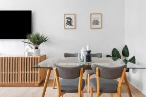 ein Esszimmer mit Glastisch und Stühlen in der Unterkunft Coastal Corner - Contemporary Chic by the Beach in Sydney