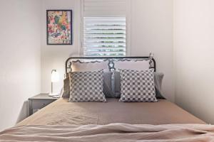 ein Schlafzimmer mit einem Bett mit Kissen und einem Fenster in der Unterkunft Coastal Corner - Contemporary Chic by the Beach in Sydney