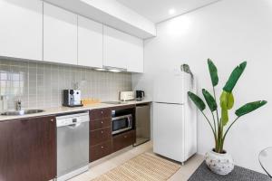 une cuisine avec des armoires blanches et un réfrigérateur blanc dans l'établissement Lux Waterfront - prime location Pool Gym & Sauna, à Cairns
