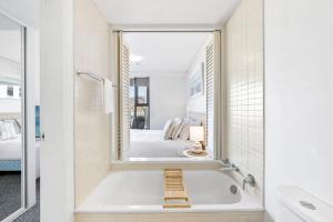 - une salle de bains blanche avec baignoire et une chambre dans l'établissement Lux Waterfront - prime location Pool Gym & Sauna, à Cairns 13 autres photos