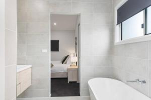 a bathroom with a tub and a sink and a bed at South Beach Escape - Sensational Shell Cove Living in Shellharbour +38 photos