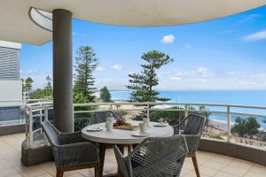a table and chairs on a balcony with a view of the ocean at Ocean Vista Escape - A Lofty Beachfront Penthouse in Wollongong