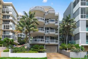 an apartment building with palm trees in front of it at Ocean Vista Escape - A Lofty Beachfront Penthouse in Wollongong