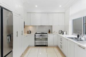 a white kitchen with a stove and a sink at Ocean Vista Escape - A Lofty Beachfront Penthouse in Wollongong