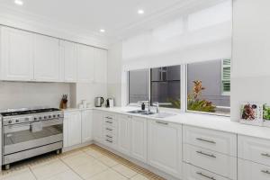 a white kitchen with white cabinets and stainless steel appliances at Ocean Vista Escape - A Lofty Beachfront Penthouse in Wollongong