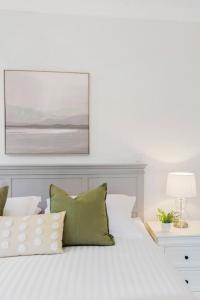 a white bed with green and white pillows on it at Ocean Vista Escape - A Lofty Beachfront Penthouse in Wollongong