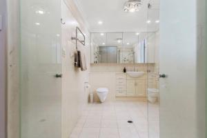 a bathroom with a shower and a toilet and a sink at Ocean Vista Escape - A Lofty Beachfront Penthouse in Wollongong