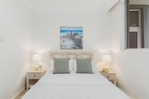 a bedroom with a white bed with two night stands at Ocean Vista Escape - A Lofty Beachfront Penthouse in Wollongong