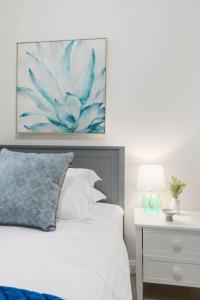 a bedroom with a bed with a painting on the wall at Ocean Vista Escape - A Lofty Beachfront Penthouse in Wollongong