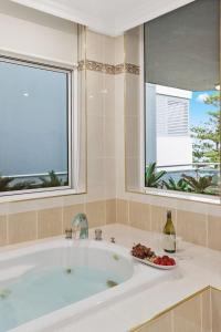 a bath tub with a window and a plate of fruit at Ocean Vista Escape - A Lofty Beachfront Penthouse in Wollongong