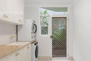 a white kitchen with a door with a window at Ocean Vista Escape - A Lofty Beachfront Penthouse in Wollongong