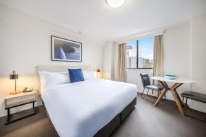 悉尼Oaks Sydney Castlereagh Suites的一间配有大床和桌子的酒店房间