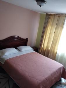1 dormitorio con 1 cama con edredón rosa y ventana en Hotel Torre Bolívar, en Pasto