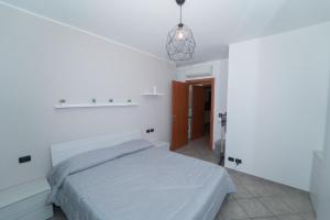 a white bedroom with a bed and a pendant light at Stile e comfort! in Trecate