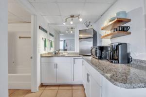 a kitchen with white cabinets and a granite counter top at The Sea & Breeze:1 Bed Condo w/Pool Steps to Beach in Tybee Island