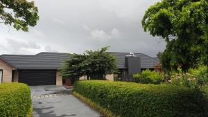 a house with a black roof and some bushes at West Melton Bed and Breakfast in West Melton