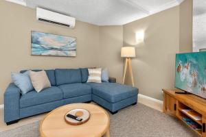 sala de estar con sofá azul y mesa en Reef Apartment Cairns en Edge Hill