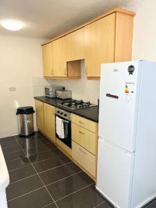 uma cozinha com um frigorífico branco e armários de madeira em Cozy 3BR Urban Oasis in the City Hub em Manchester