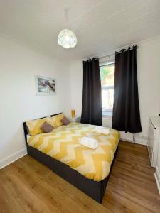 um quarto com uma cama amarela e preta e uma janela em Cozy 3BR Urban Oasis in the City Hub em Manchester