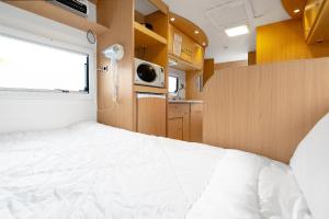 ein Schlafzimmer mit einem weißen Bett in einem Wohnwagen in der Unterkunft Poseidon Caravan in Gapyeong