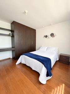 a bedroom with a large white bed with a blue blanket at Home Ibarra Parque Ciudad Blanca in Ibarra