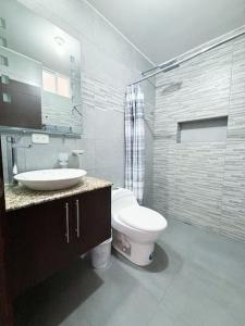 a bathroom with a toilet and a sink at Home Ibarra Parque Ciudad Blanca in Ibarra