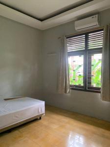1 dormitorio con cama blanca y ventana en Homestay Mutiara en Yogyakarta
