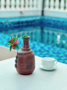 Tân Thành (1)的住宿－Blue Fish Villa，花瓶,花在茶杯旁边的桌子上