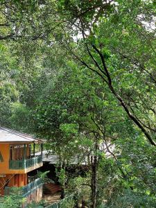 a house with a balcony in the middle of trees at Belihuloya Terico Resort in Balangoda
