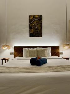een groot wit bed met een blauw kussen erop bij Lovely villa 1 minute from the beach in Canggu