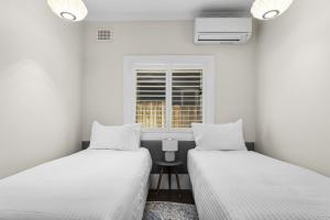 2 Betten in einem kleinen Zimmer mit Fenster in der Unterkunft Comfy 2-Bed Apartment with AC throughout in Sydney
