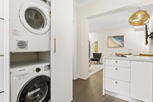 uma lavandaria branca com máquina de lavar e secar roupa em Comfy 2-Bed Apartment with AC throughout em Sydney