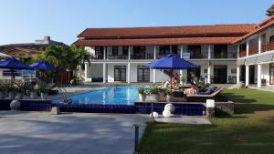 um par de pessoas sentadas sob guarda-chuvas à beira de uma piscina em IMAGINE Villa Hotel em Mirissa