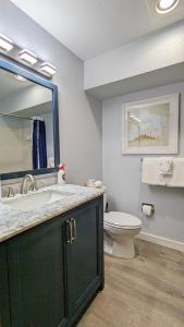 a bathroom with a sink and a toilet and a mirror at Calypso at Nautilus - Pet Friendly, Walk to beach! in Ocean Shores