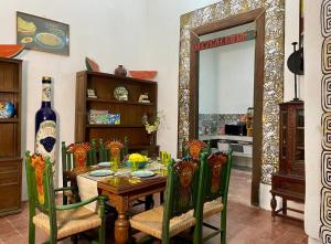 a dining room with a table with chairs and a bottle of wine at Casa Iktal Luxury - Centro Mérida in Mérida