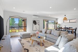 ein Wohnzimmer mit einer Couch und einem Tisch in der Unterkunft Point Cook's Spacious and Comfy 4BR/3BA Haven! in Point Cook