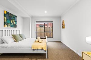 ein weißes Schlafzimmer mit einem Bett und einem Fenster in der Unterkunft Point Cook's Spacious and Comfy 4BR/3BA Haven! in Point Cook + 17 Fotos
