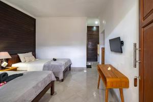 a hotel room with two beds and a table at Widia Homestay Nusa Lembongan in Nusa Lembongan