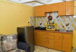una pequeña cocina con armarios de madera y nevera. en Qwetu Homes, en Keruguya