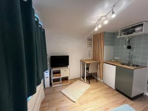 a room with a kitchen with a sink and a tv at Studio proche du centre-ville in Arpajon