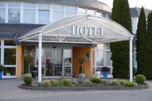 une entrée de l'hôtel avec un panneau à l'avant dans l'établissement AVALON Hotelpark Königshof, à Königslutter am Elm