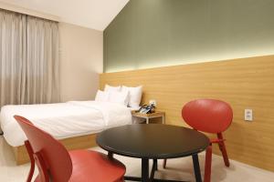 a hotel room with a bed and a table and chairs at Calm Rest Hotel Gimhae in Gimhae