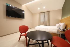 una camera d'albergo con letto, tavolo e sedie di Calm Rest Hotel Gimhae a Gimhae