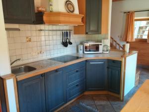 a kitchen with blue cabinets and a sink and a microwave at Apartma Brin Bovec in Bovec