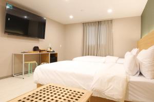 a hotel room with two beds and a flat screen tv at Calm Rest Hotel Gimhae in Gimhae
